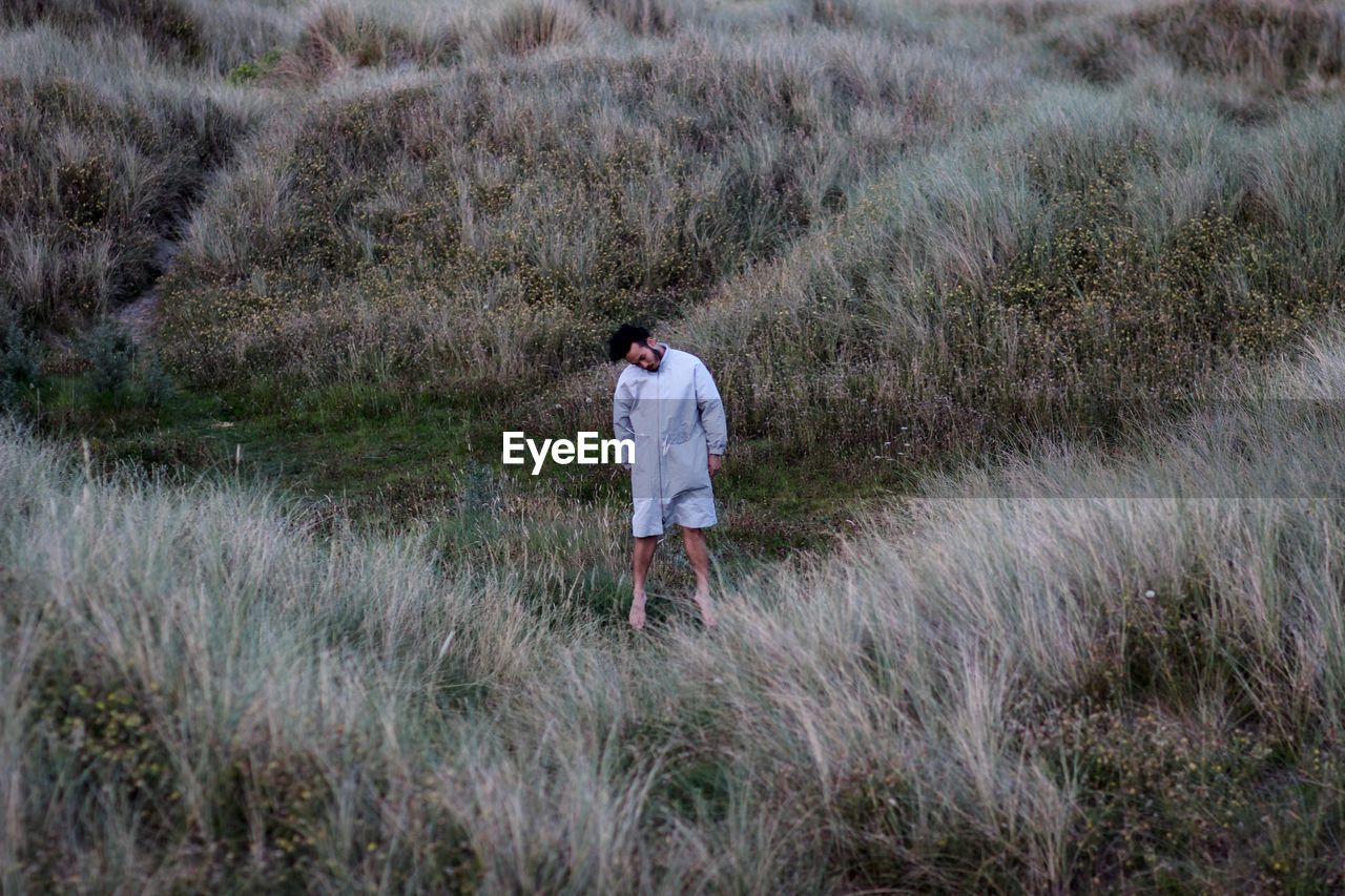 WOMAN WALKING ON GRASSY FIELD