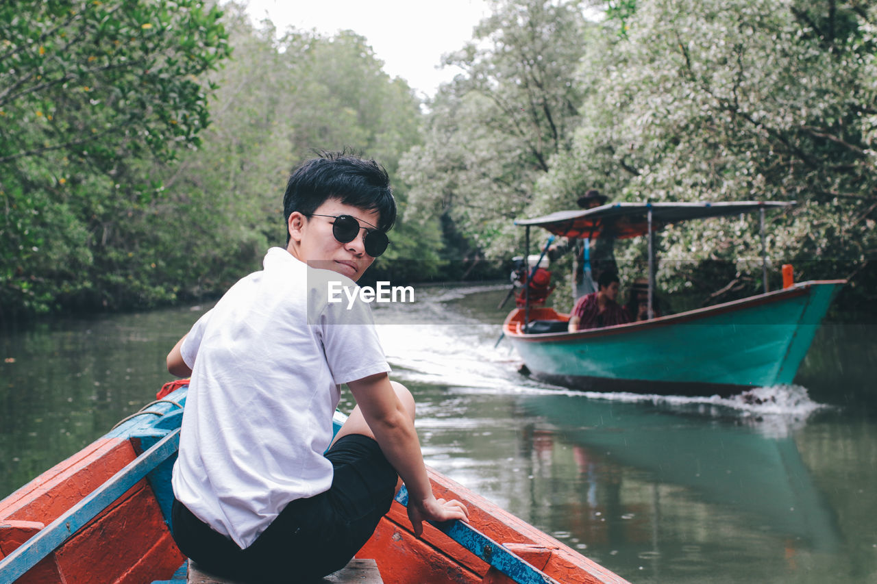 MAN SITTING ON BOAT IN RIVER