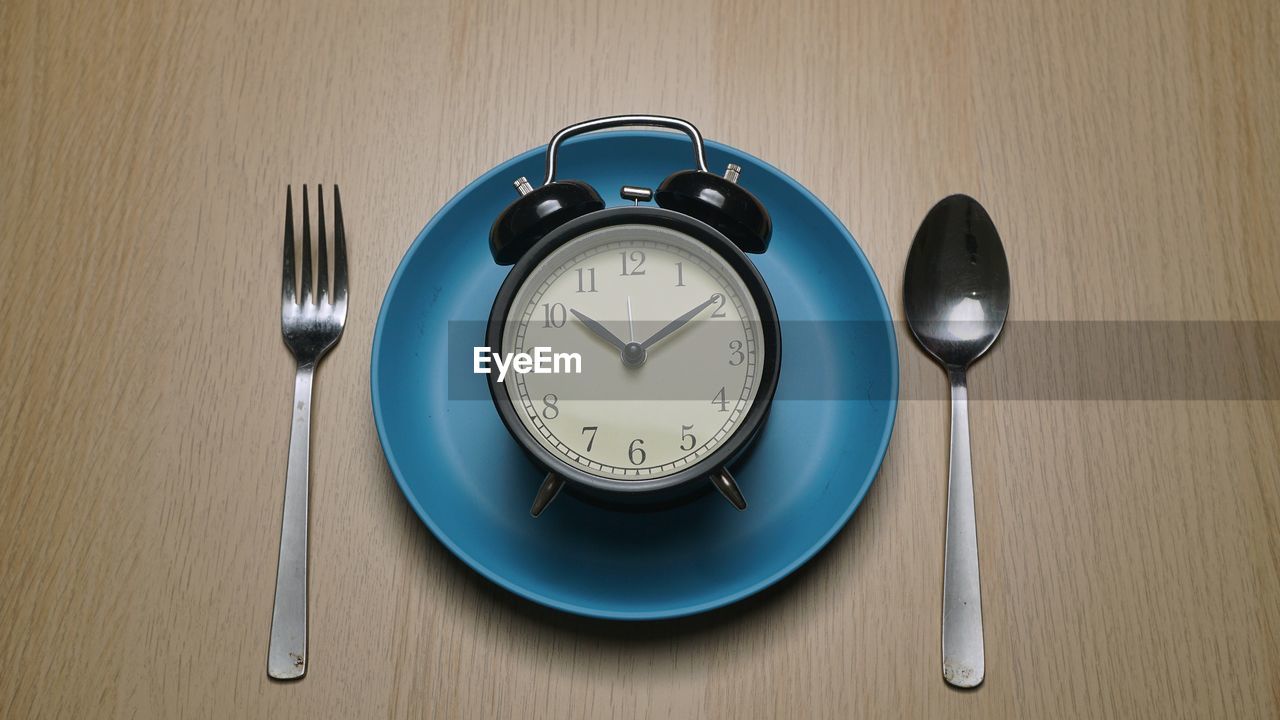 High angle view of clock on table with fork and spoon. diet concept 