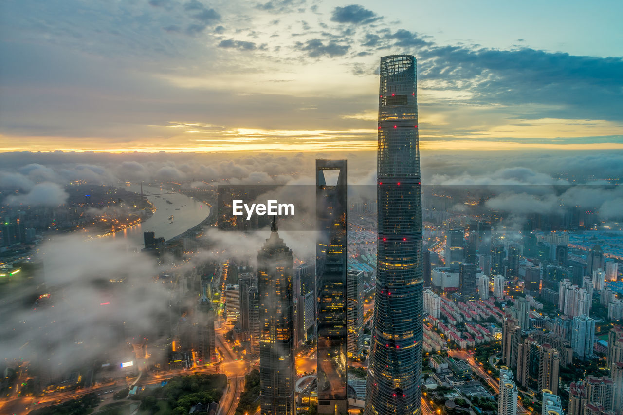 HIGH ANGLE VIEW OF BUILDINGS IN CITY AGAINST SKY DURING SUNSET