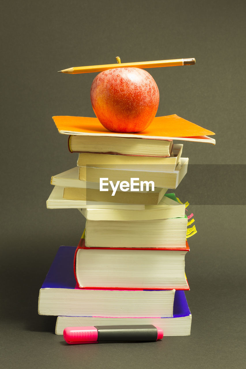 Apple on stack of books against gray background