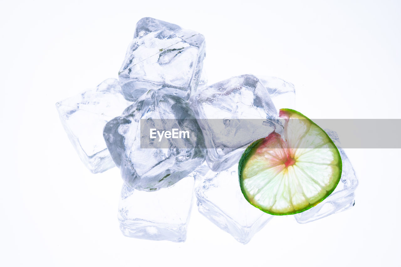 Close-up of ice cubes with lime slice against white background