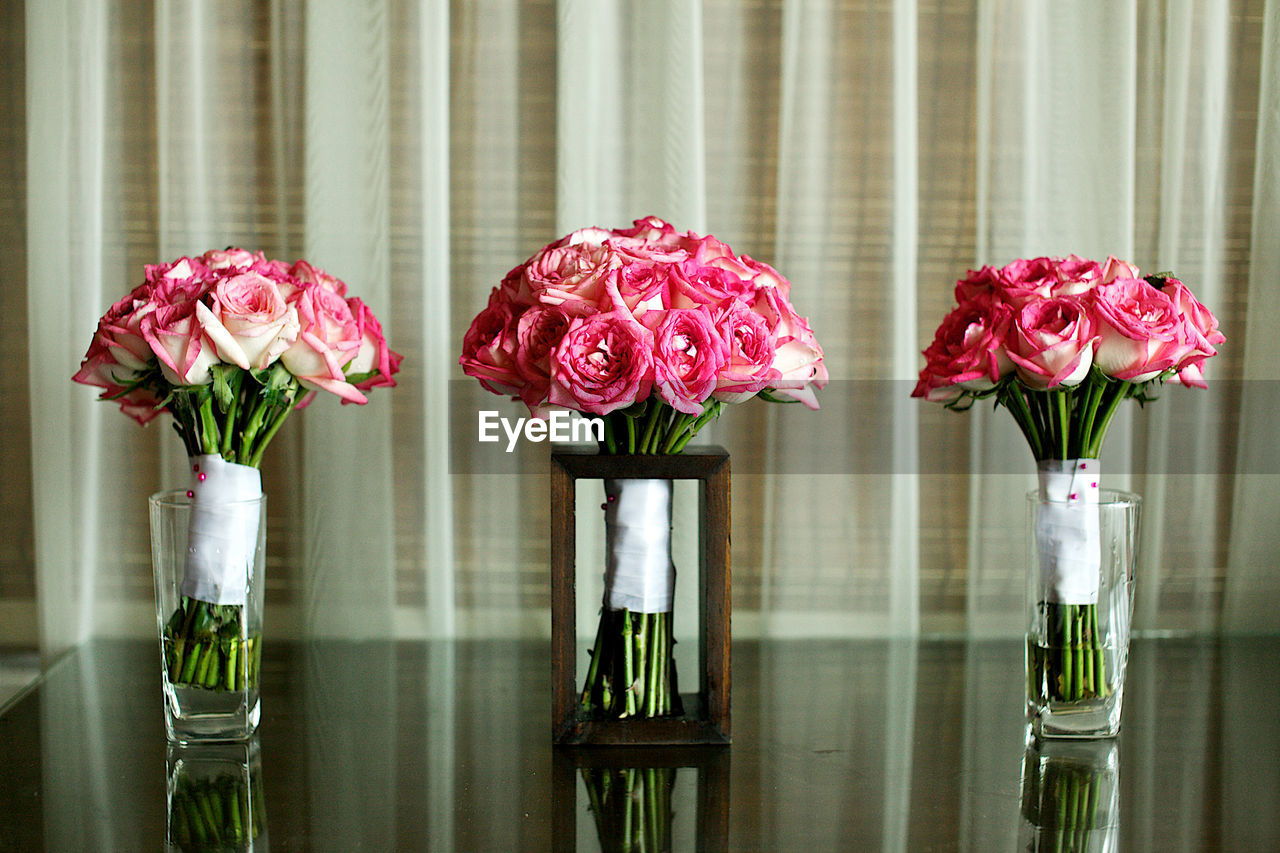 CLOSE-UP OF PINK ROSES IN VASE AGAINST WINDOW