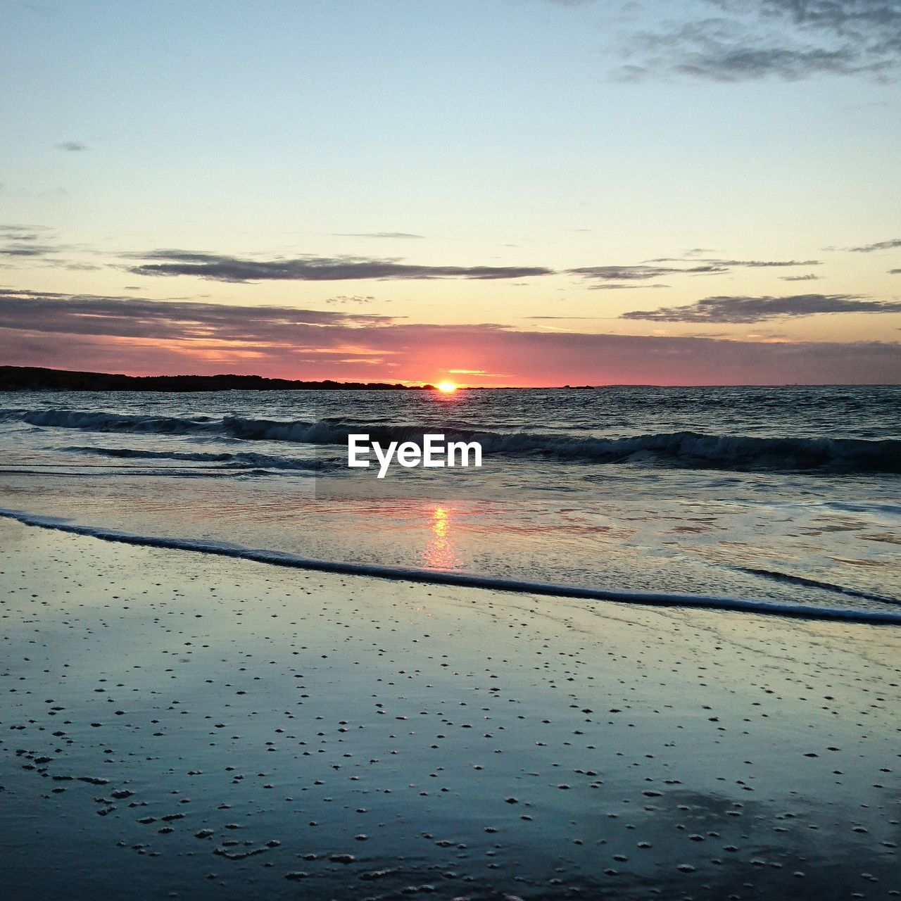 Scenic view of beach against sky at sunset