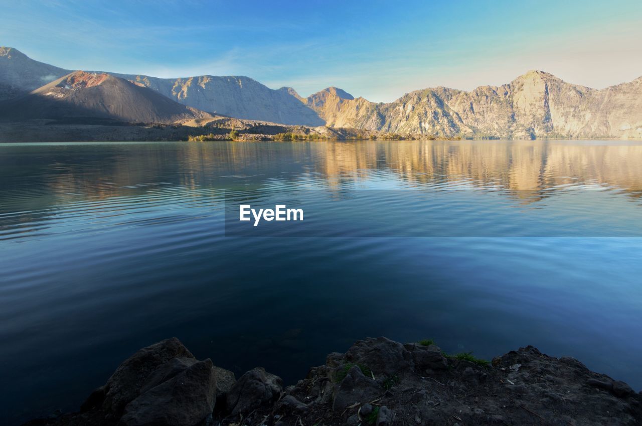 Scenic view of lake by mountains against sky