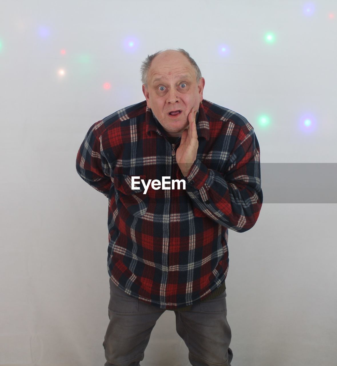 Portrait of shock man standing against illuminated wall