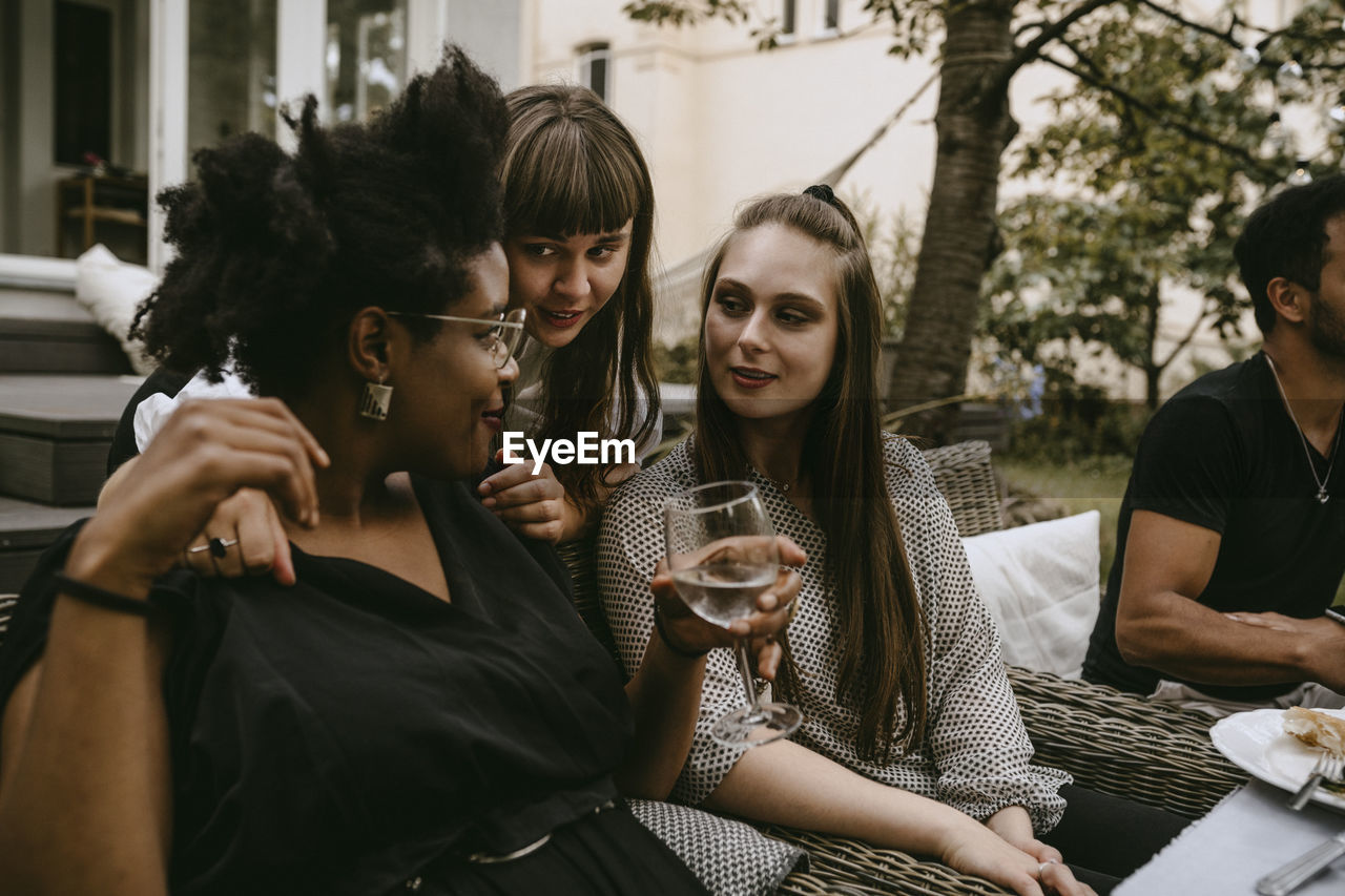 Smiling female friends talking while enjoying during garden party