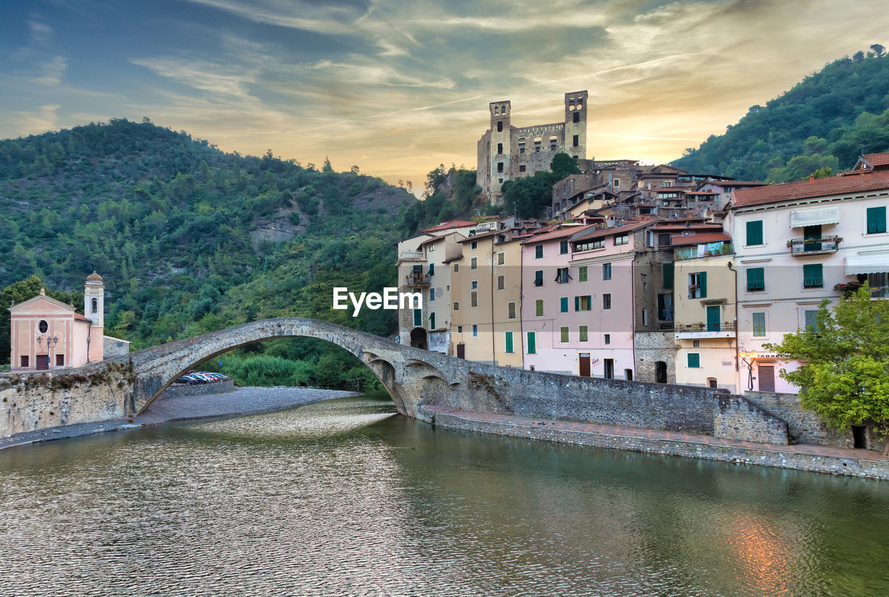 ARCH BRIDGE OVER RIVER BY BUILDINGS AGAINST SKY