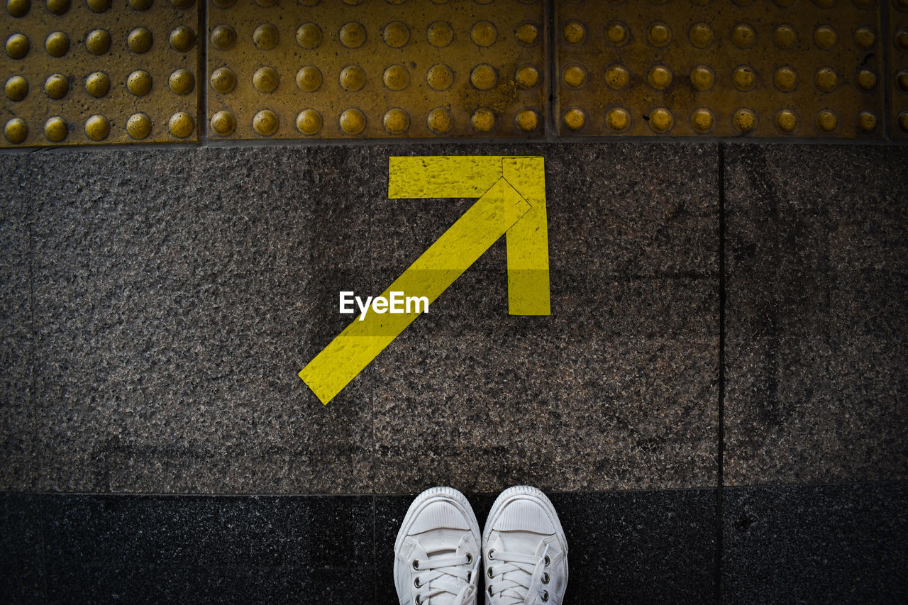 Low section of person standing on road sign