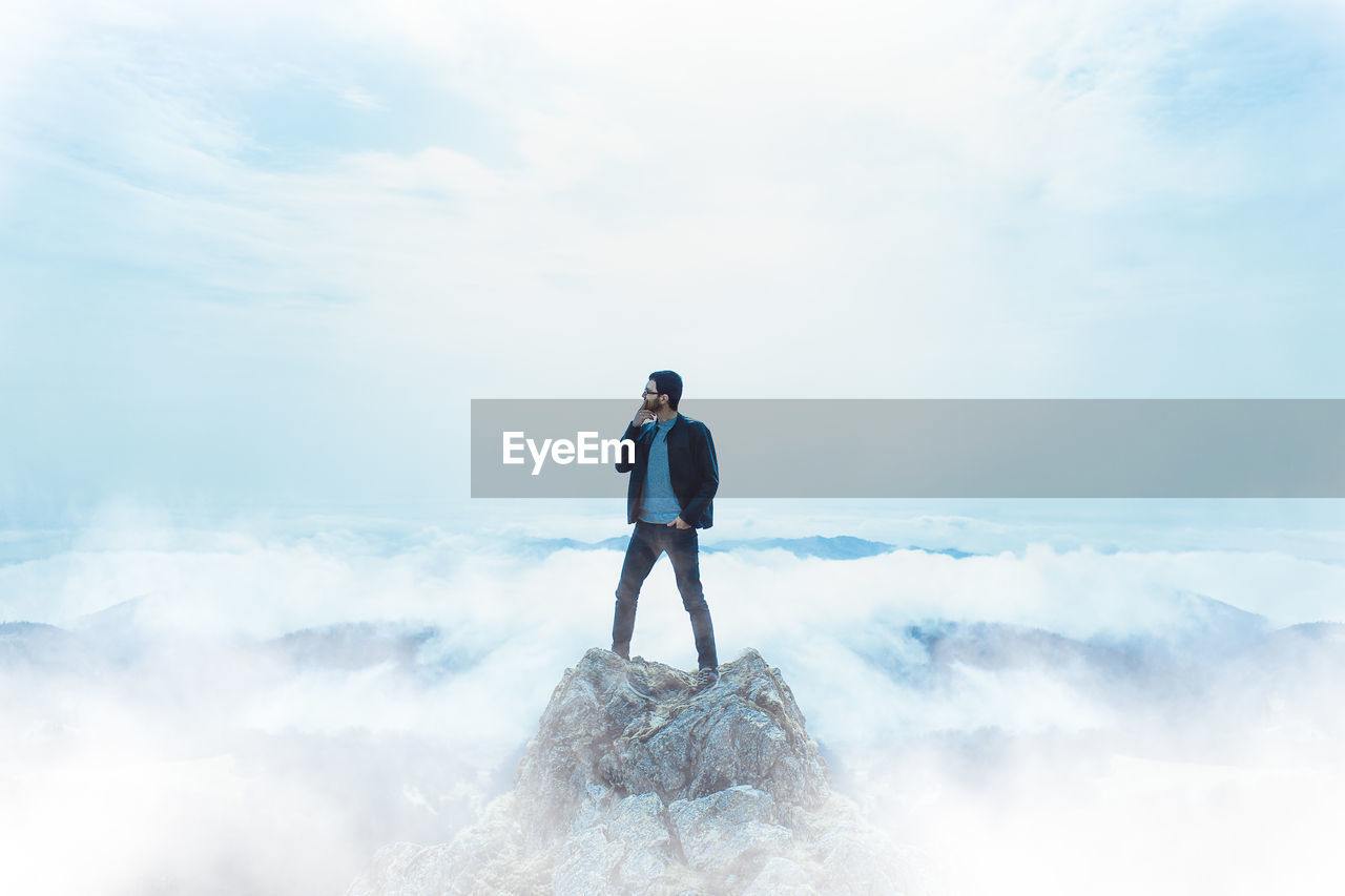 Man standing on rock against sky