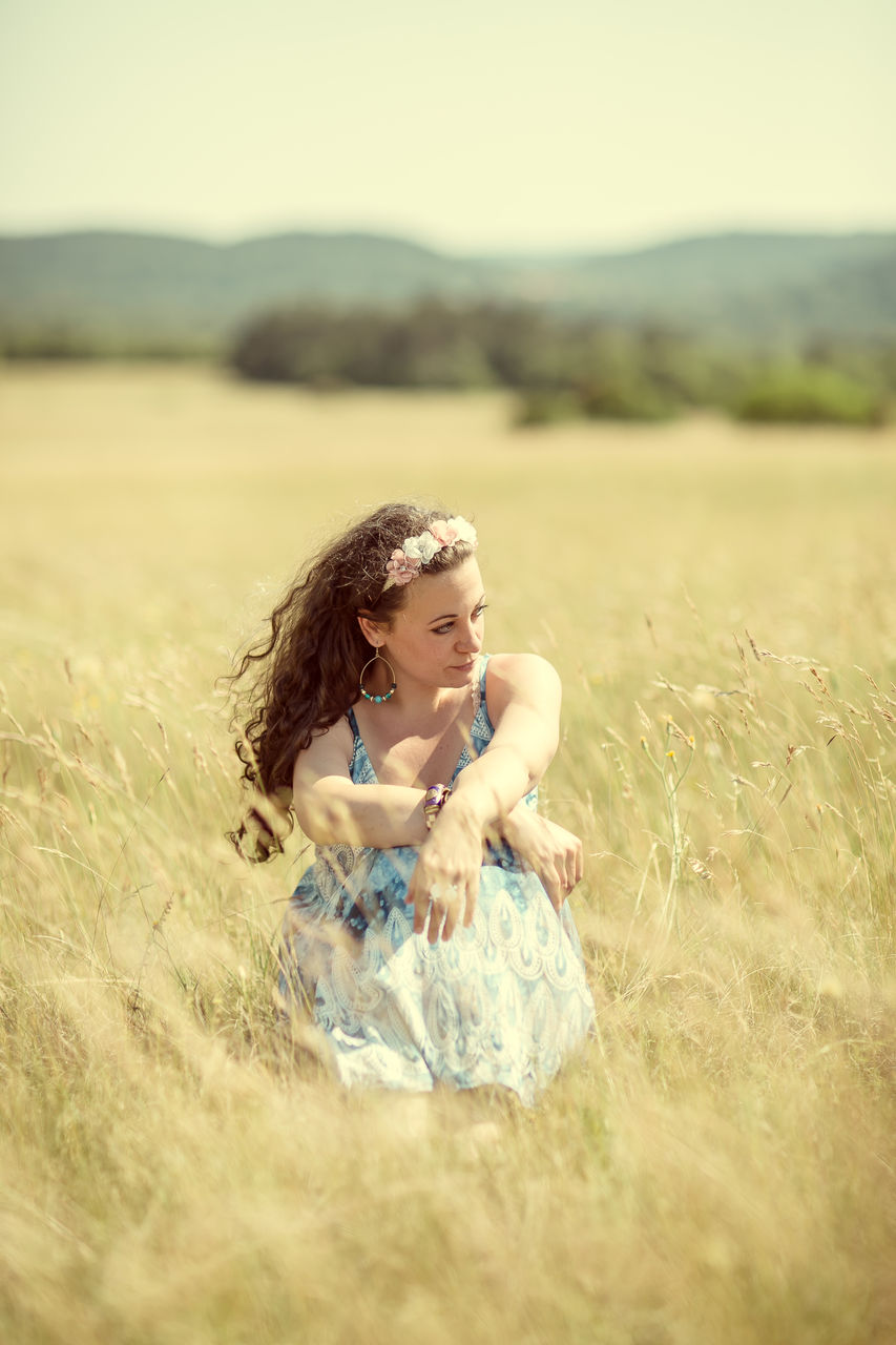 Beautiful woman sitting on grassy field 