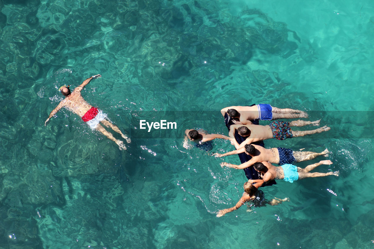 HIGH ANGLE VIEW OF PEOPLE SWIMMING POOL IN WATER