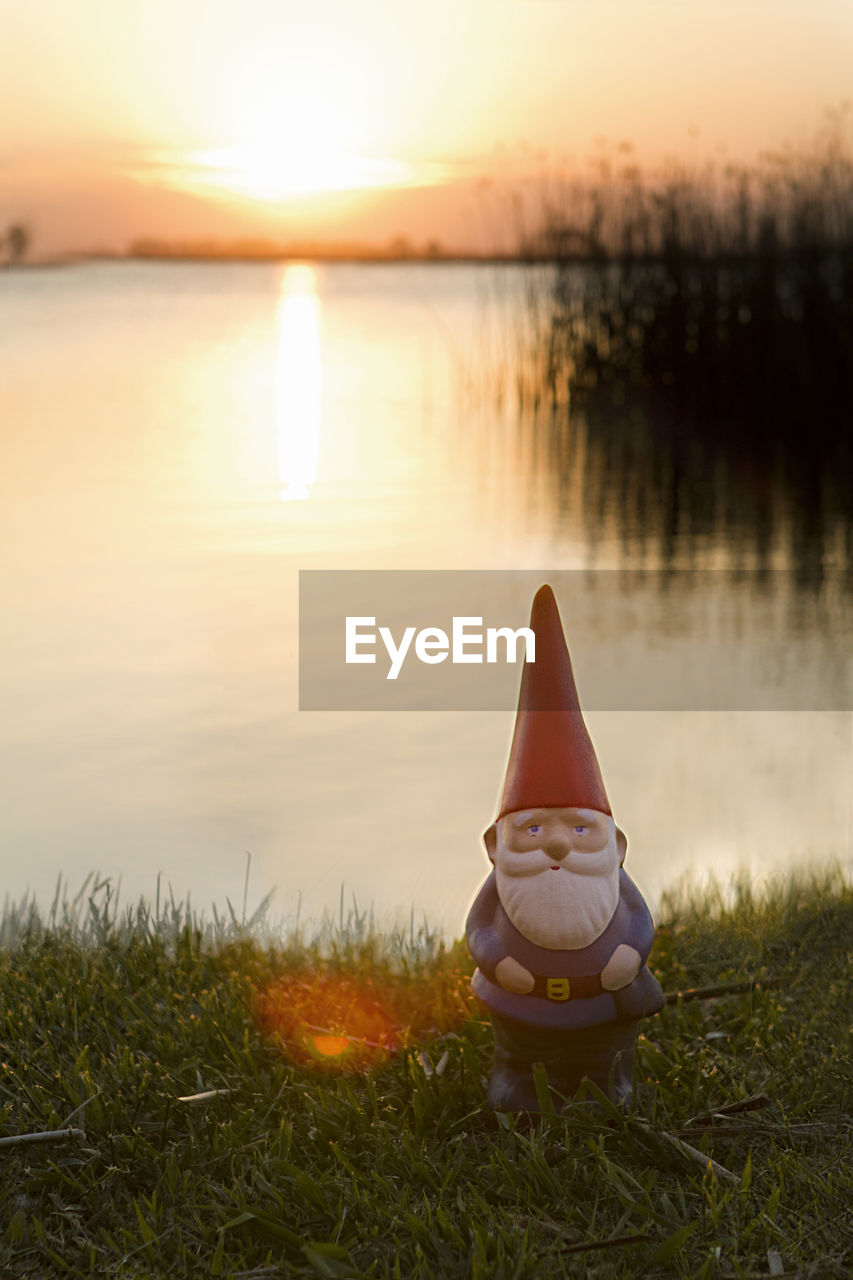 Scenic view of lake against sky during sunset with garden gnome 