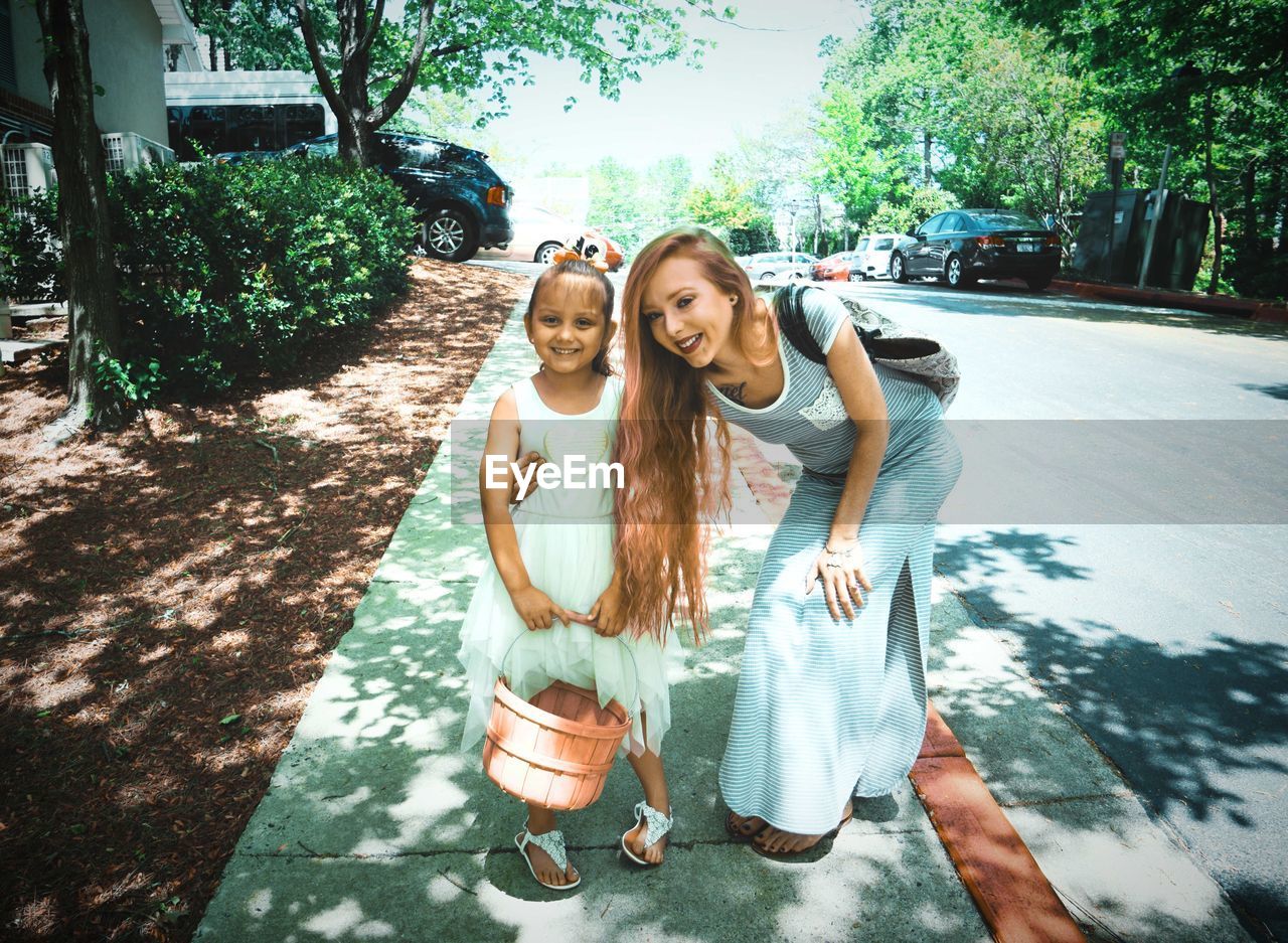 Portrait of girl with mother standing on footpath