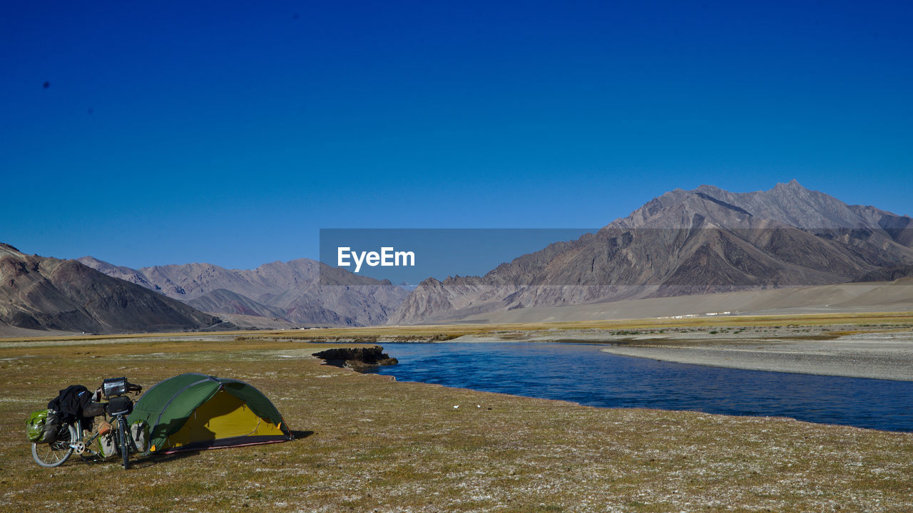 Scenic view of lake and mountains against clear blue sky