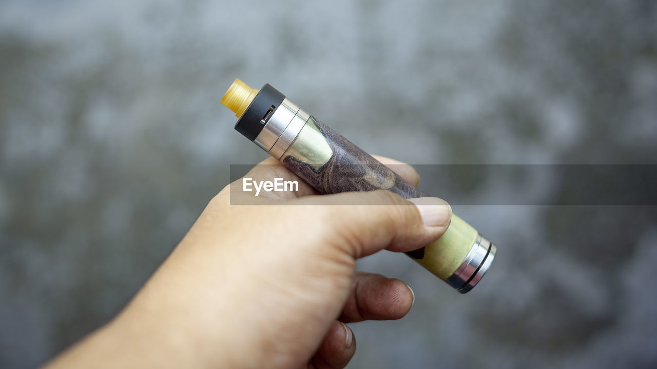 CLOSE-UP OF PERSON HAND HOLDING CIGARETTE OUTDOORS