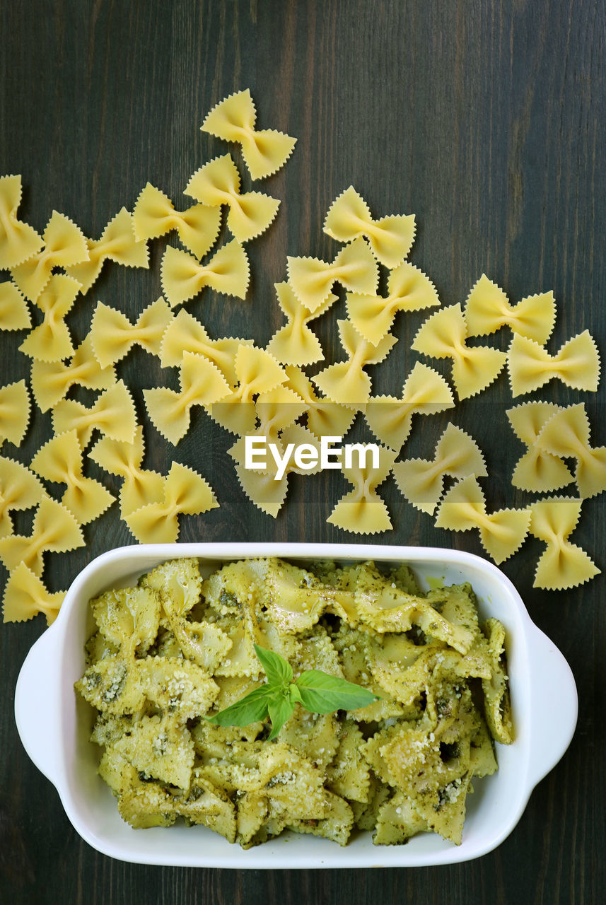 Bowl of homemade farfalle pasta with pesto sauce on wooden table