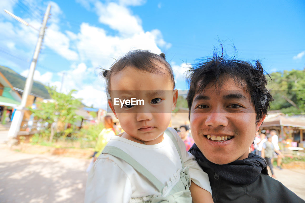 Portrait of cute girl with smiling father standing against sky