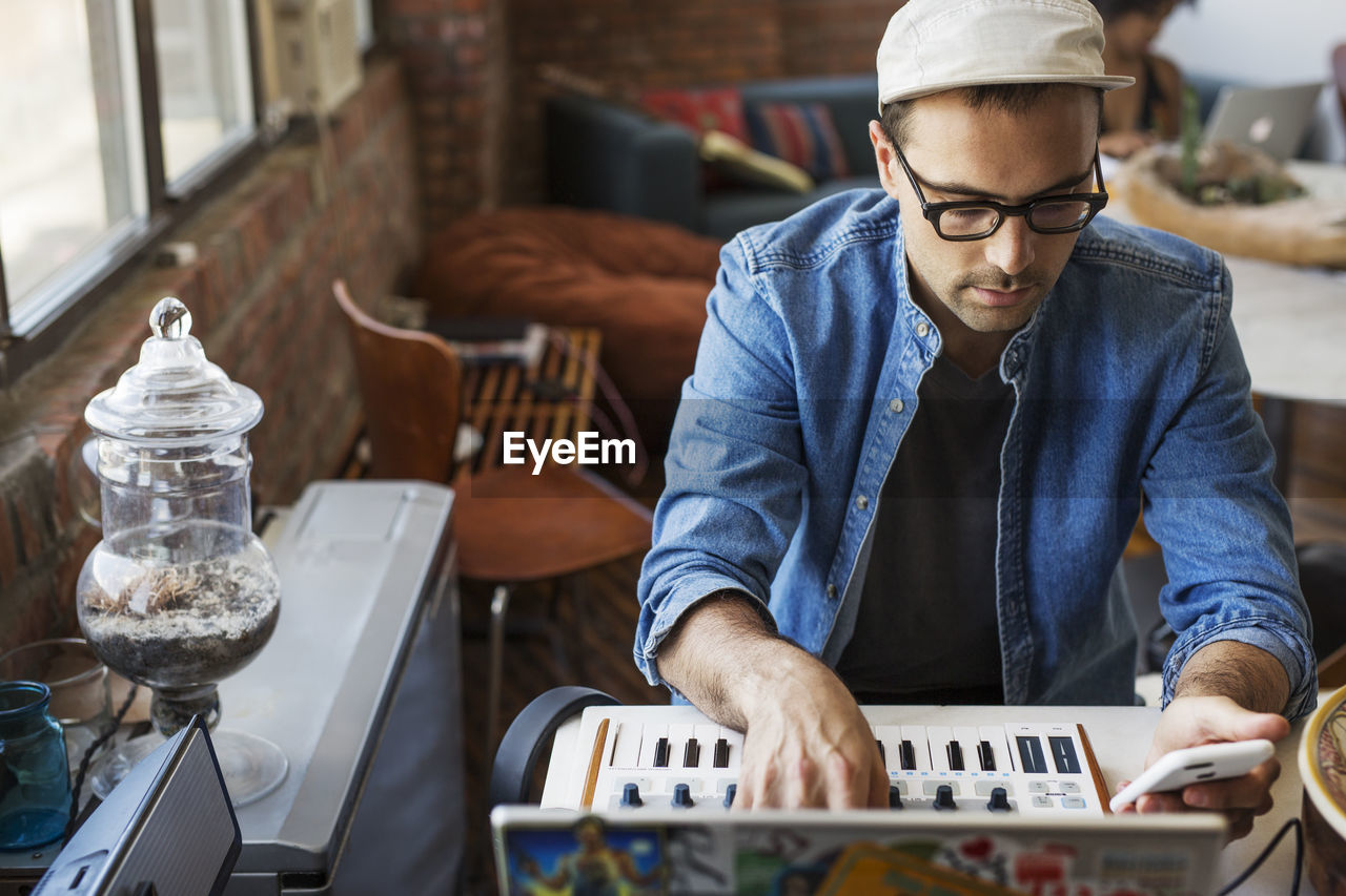 Man using mobile phone with piano at home