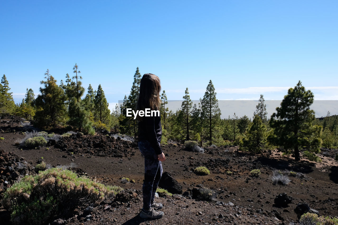Side view of woman standing on land against clear sky