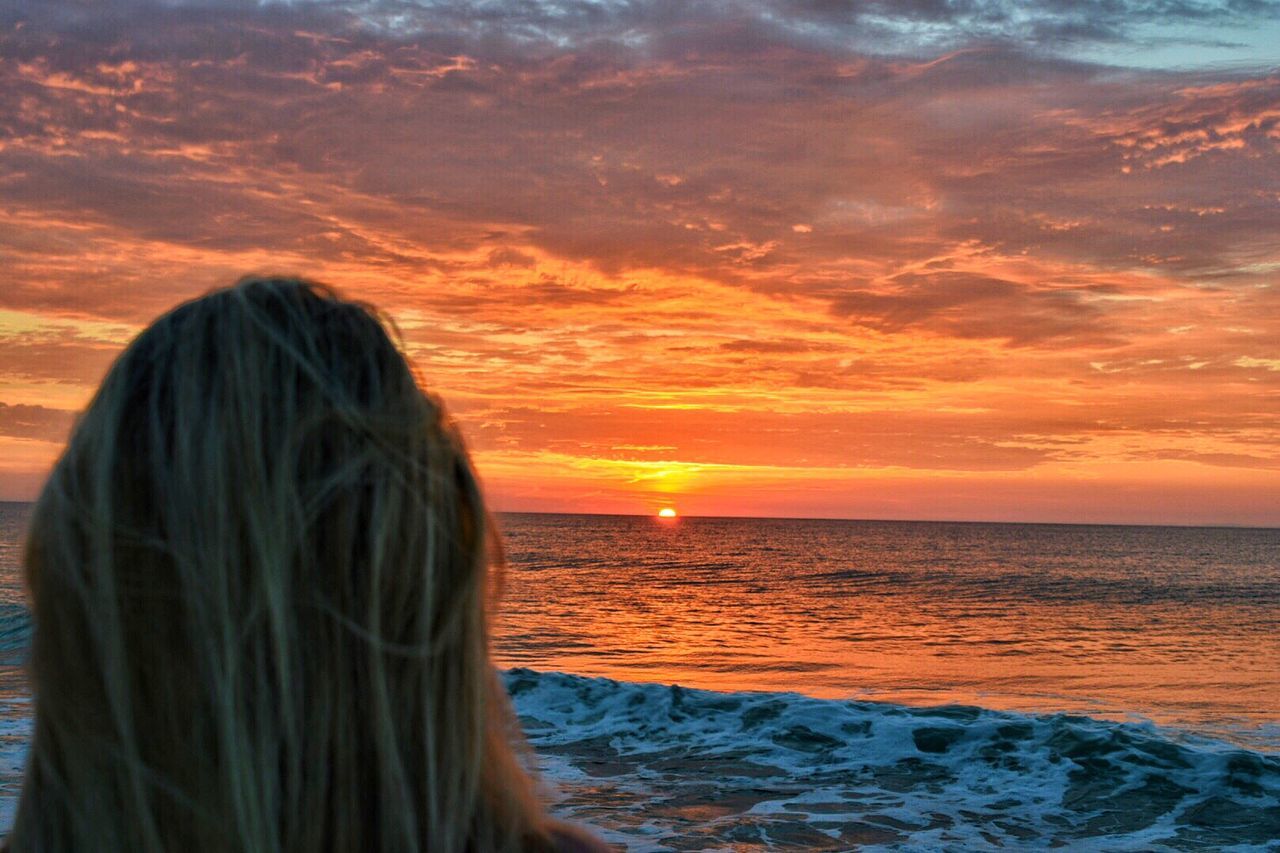 REAR VIEW OF WOMAN AGAINST ORANGE SKY