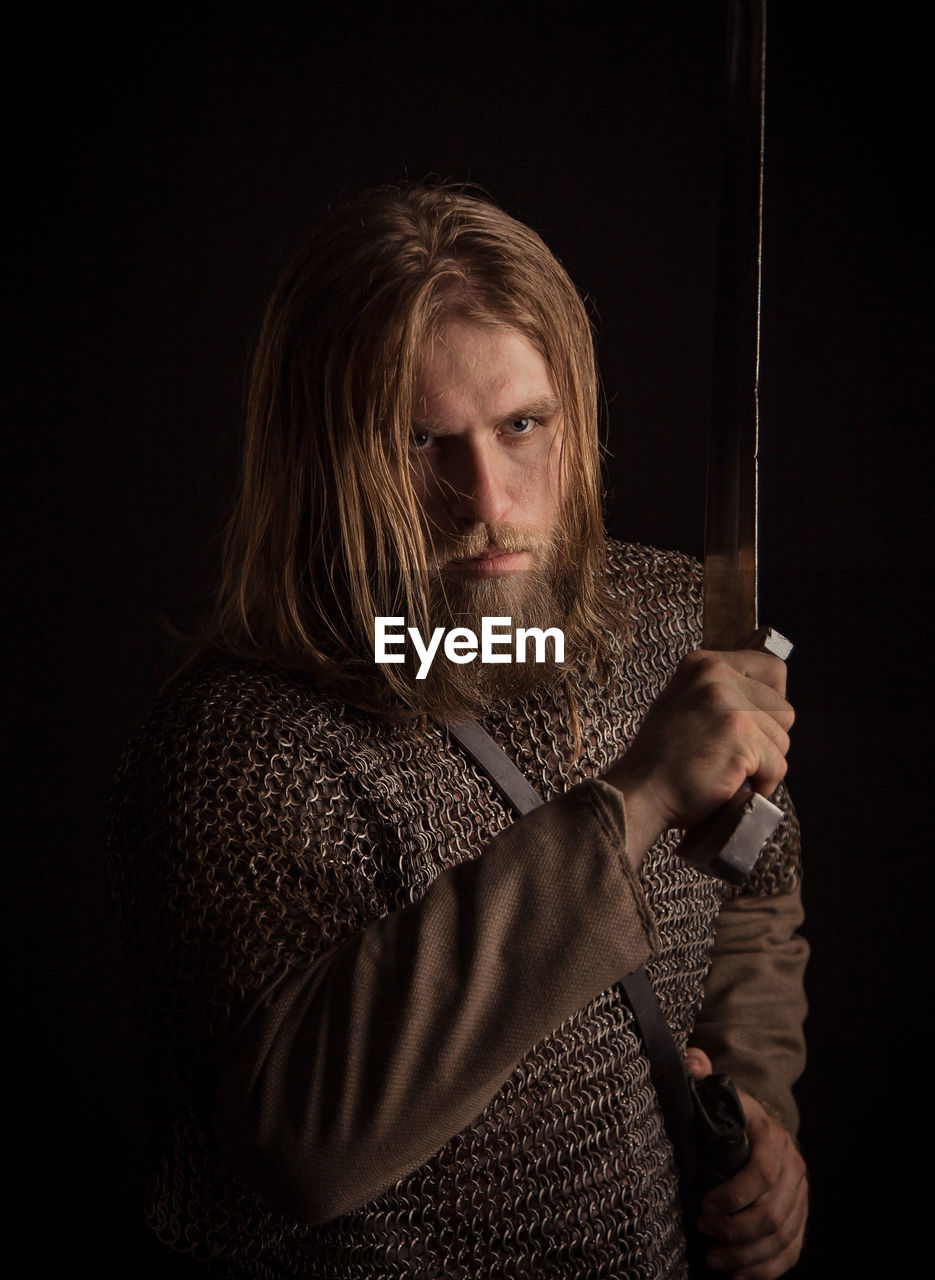 Viking holding sword against black background