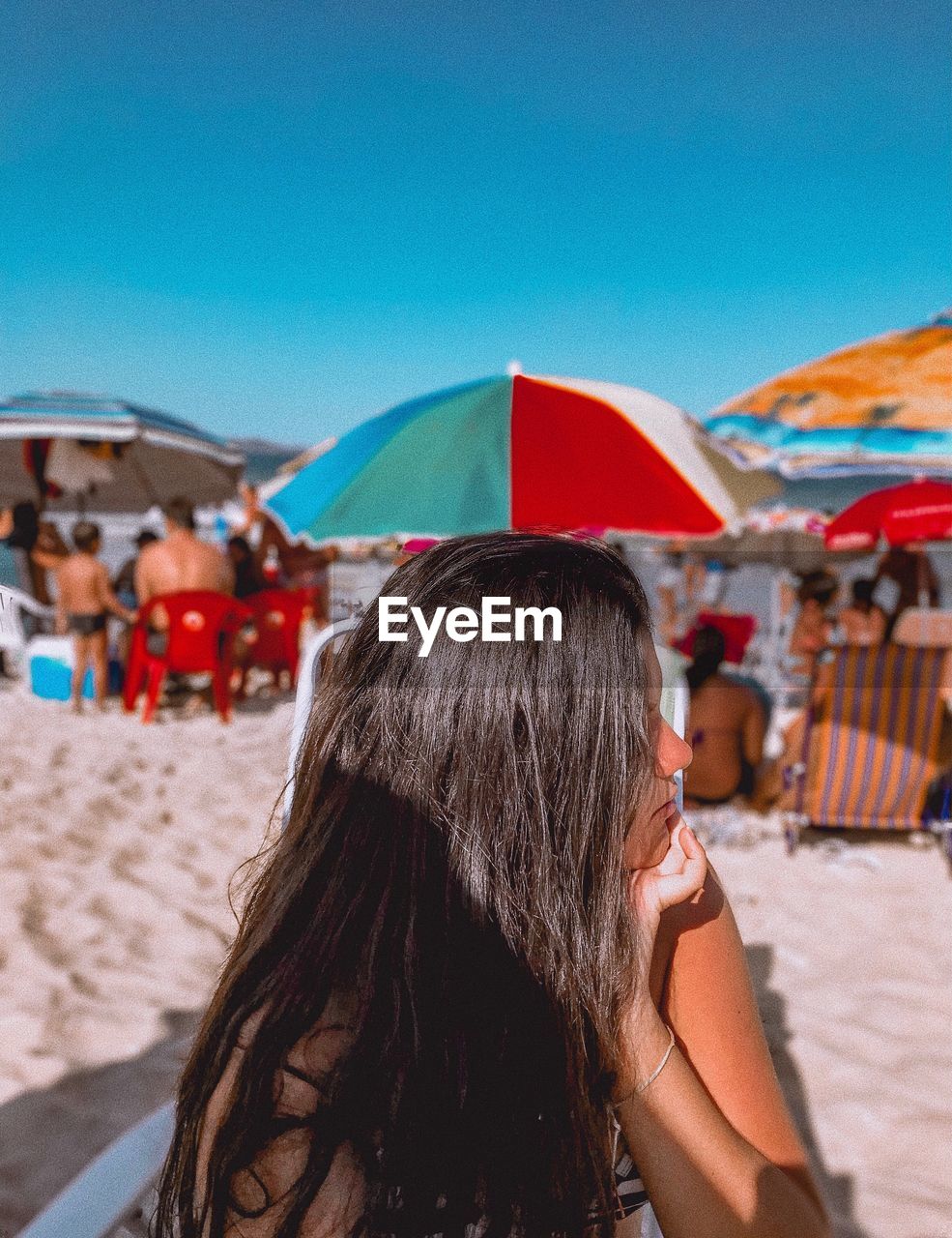 Young woman looking away while sitting at beach