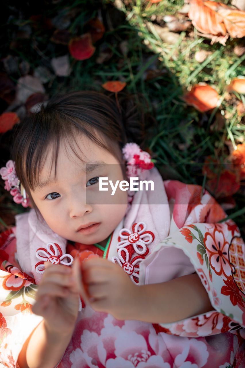 High angle portrait of cute girl lying on field