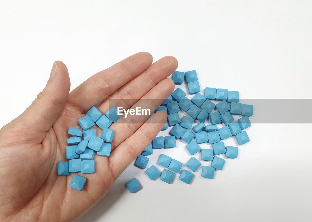 High angle view of hand holding pills over white background