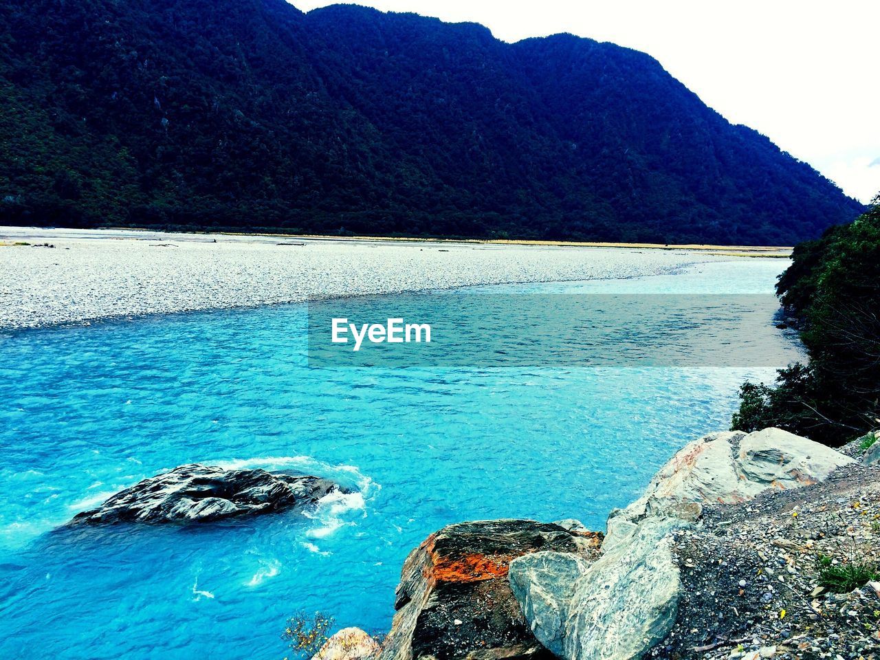 SCENIC VIEW OF SEA BY MOUNTAIN AGAINST CLEAR SKY