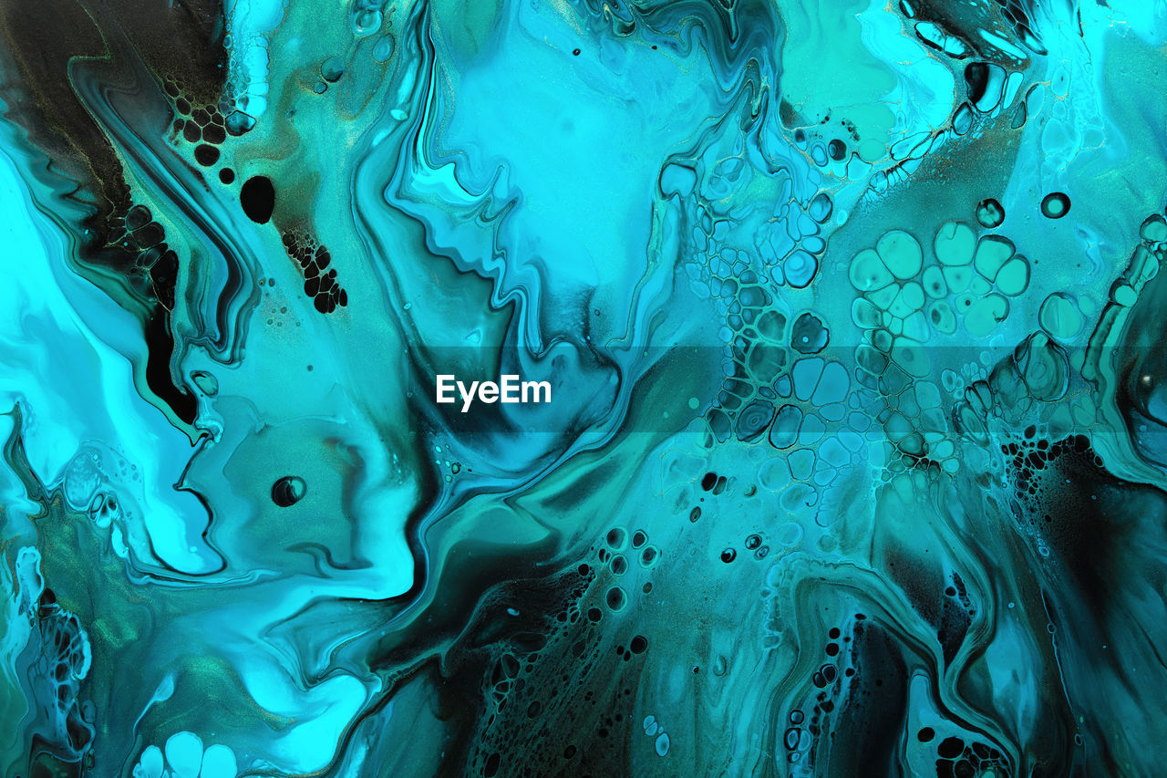 Fluid art. green and blue abstract wave swirls on black background. marble effect background or