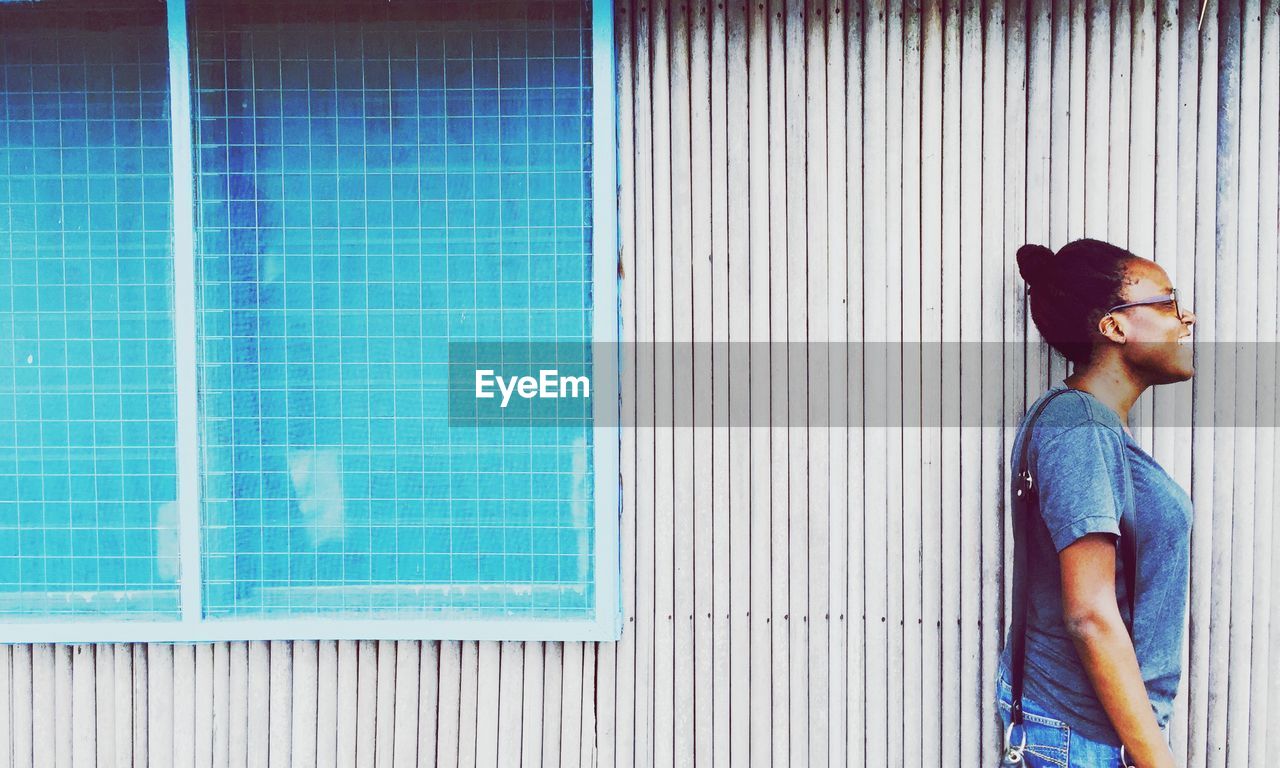 Close-up of woman looking away while standing against wall