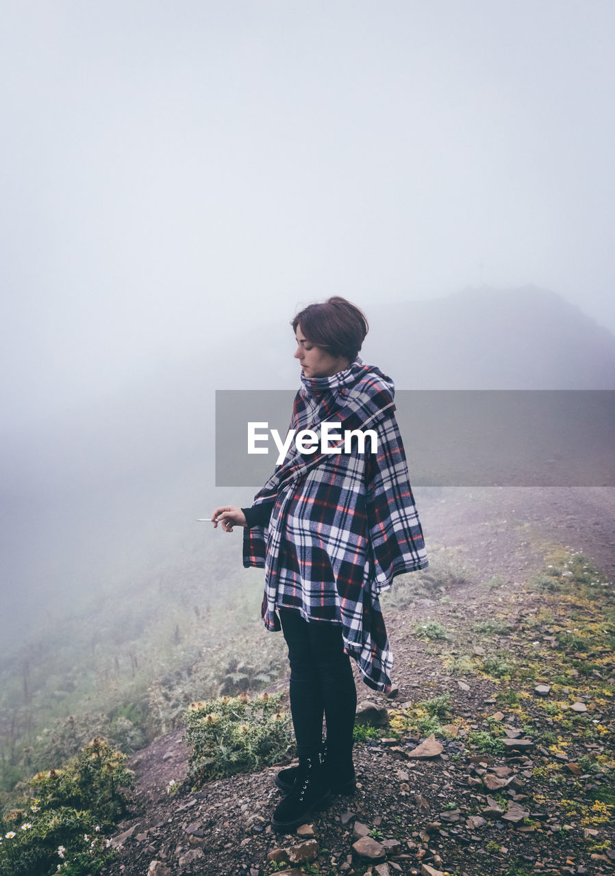 Young woman wrapped in blanket during foggy weather