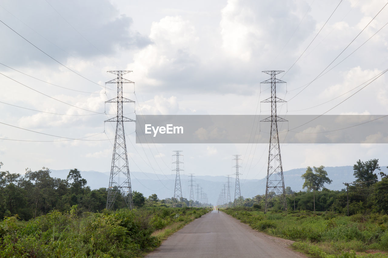 ROAD AMIDST ELECTRICITY PYLON AGAINST SKY