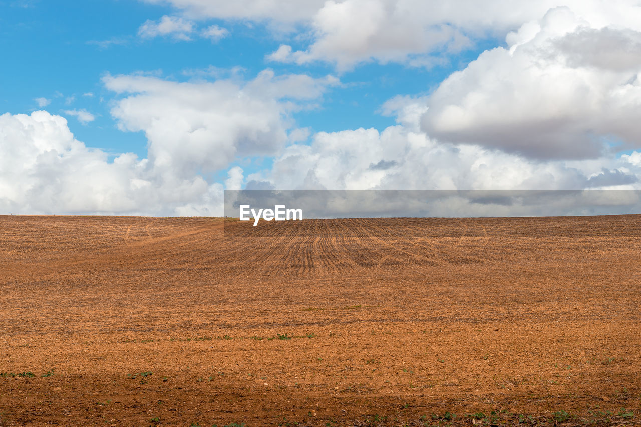 Scenic view of empty field  ready for cultivation against white cloudy sky