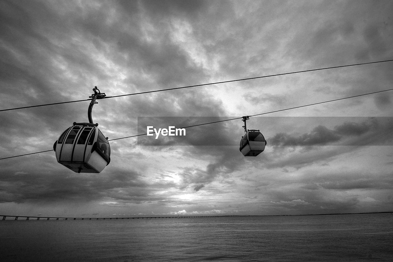 Low angle view of cable hanging over sea against sky