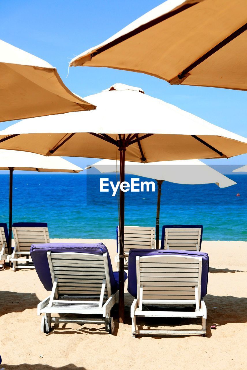 DECK CHAIRS ON BEACH AGAINST SEA