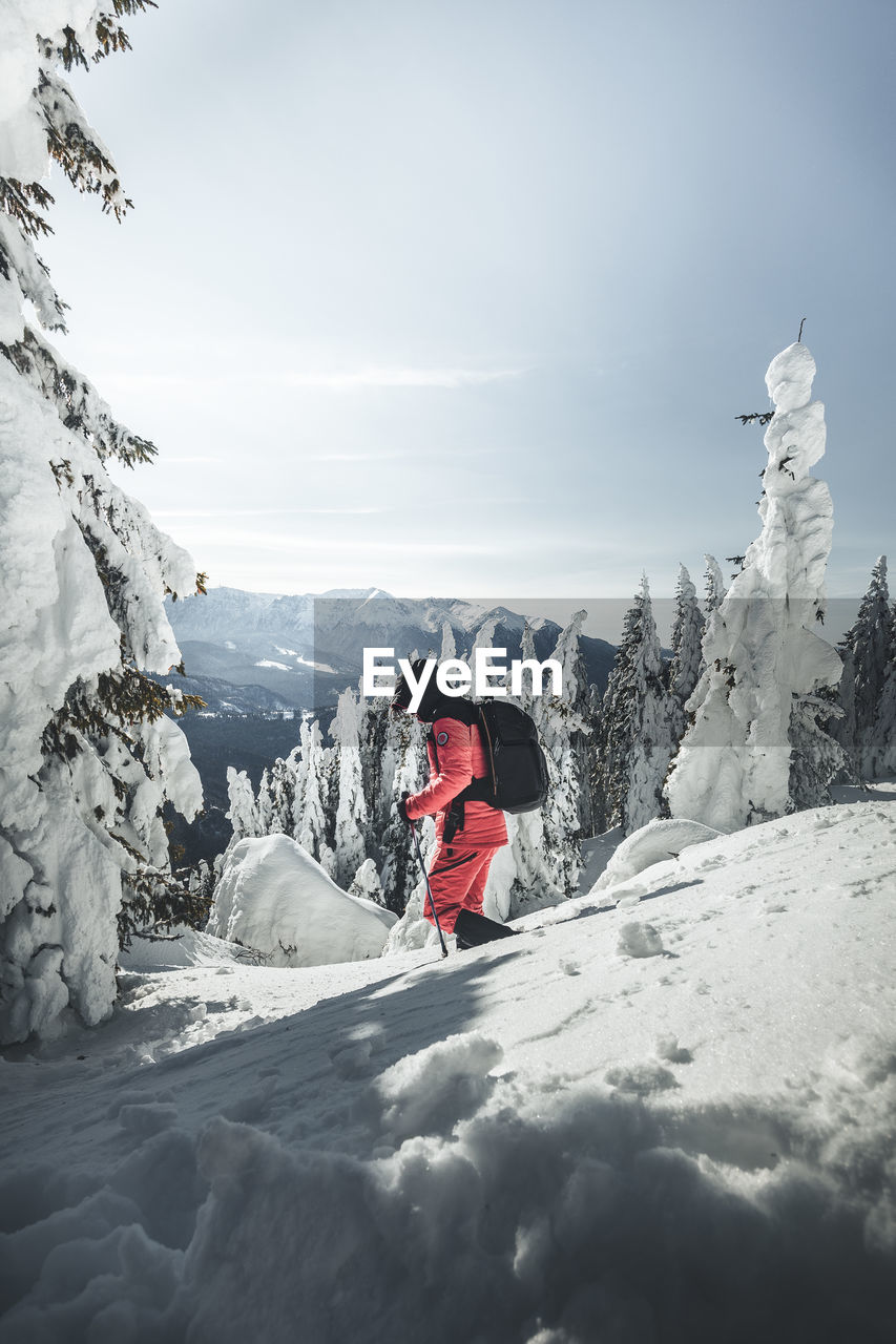 Man hiking on snowcapped mountain against sky