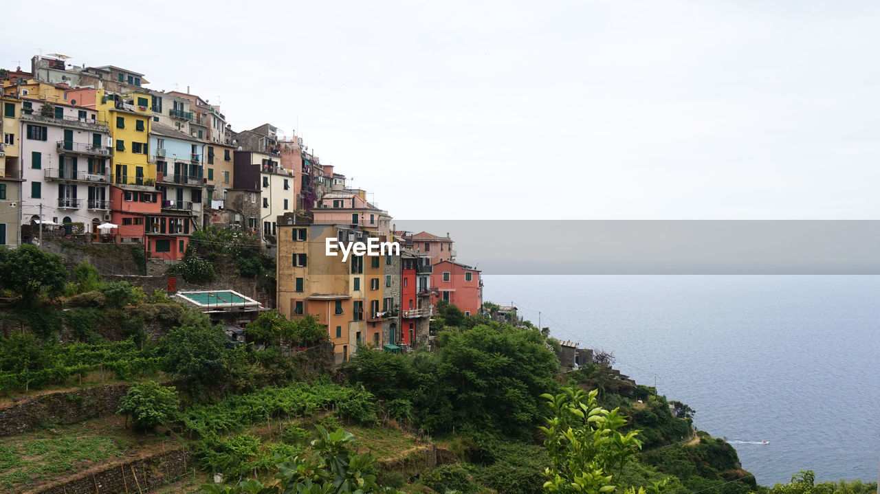 Buildings by sea against clear sky