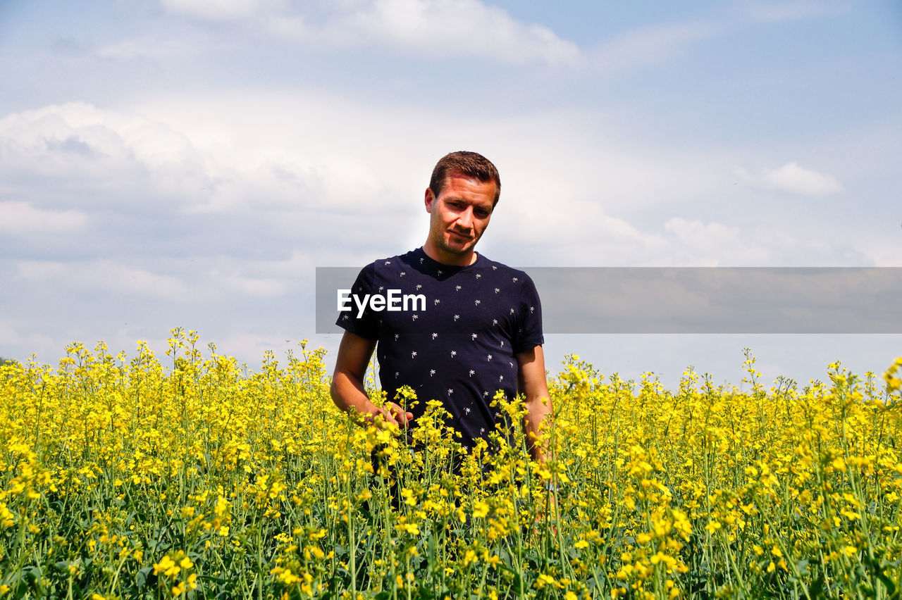 Man standing on oilseed rape field against sky