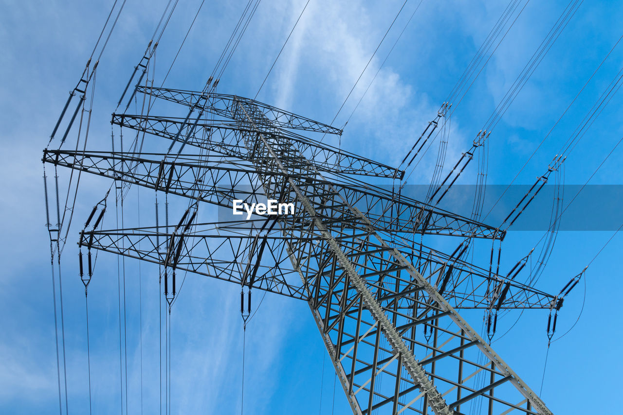 High voltage mast in front of blue sky with white clouds