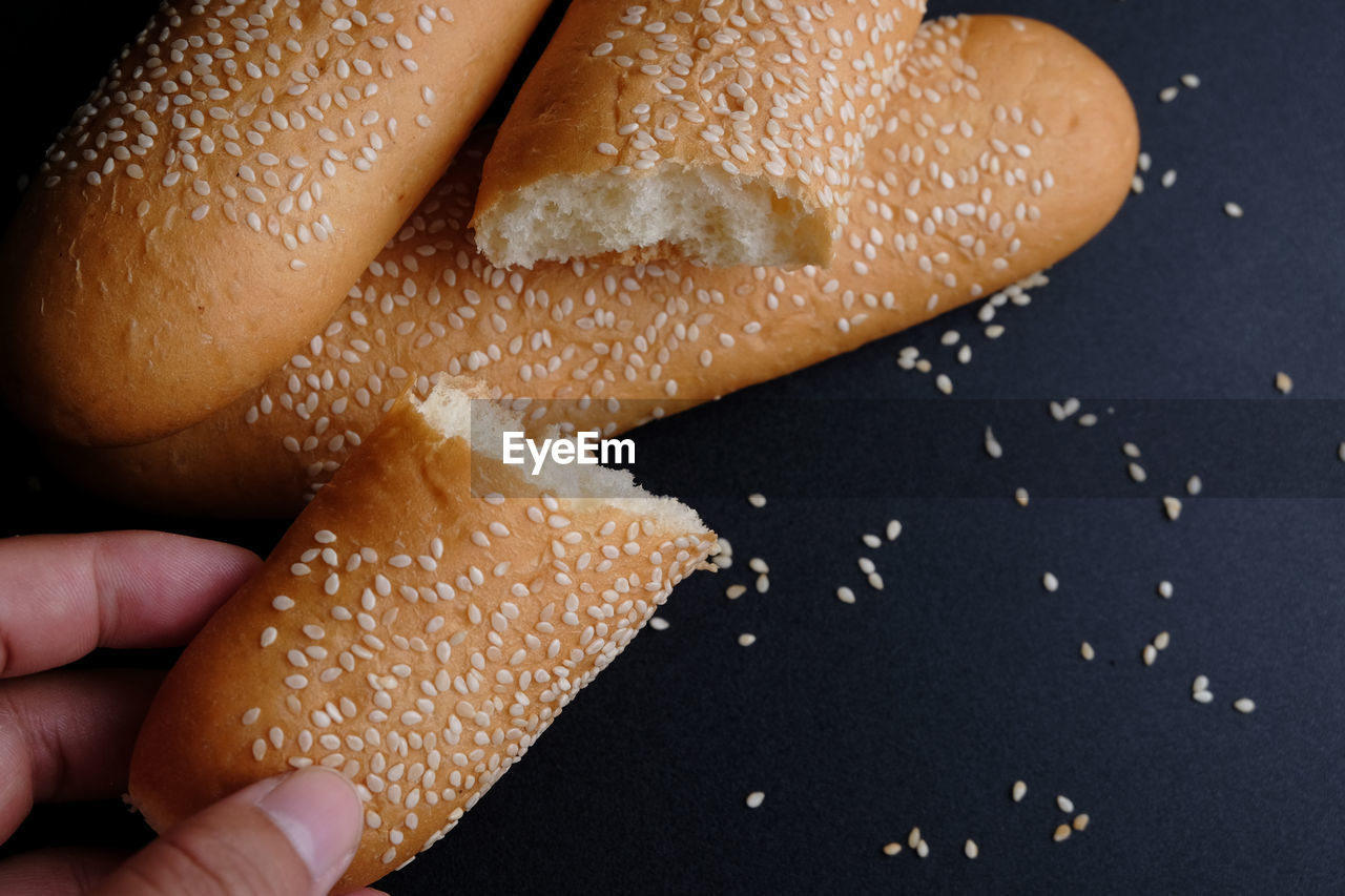 Cropped hand of person holding sliced bread on table