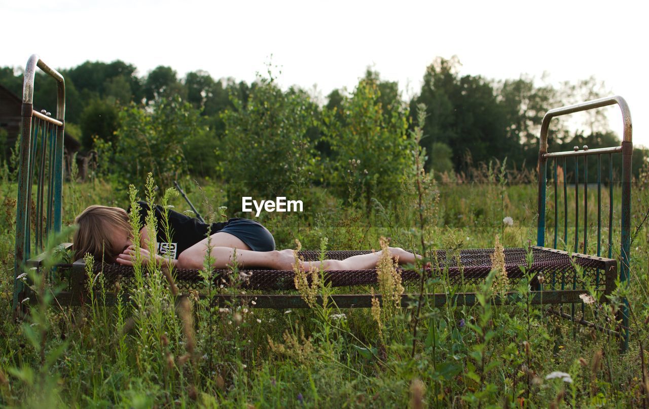 Boy lying on rusty bed at park