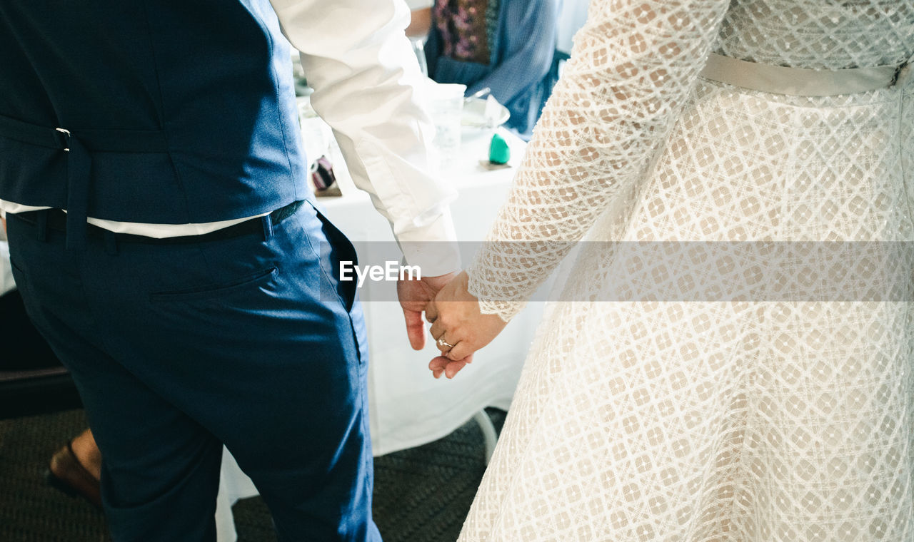 Midsection of wedding couple holding hands