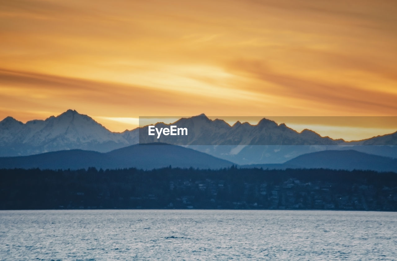 Snow covered olympic mountains over puget sound west of seattle at sunset golden hour.