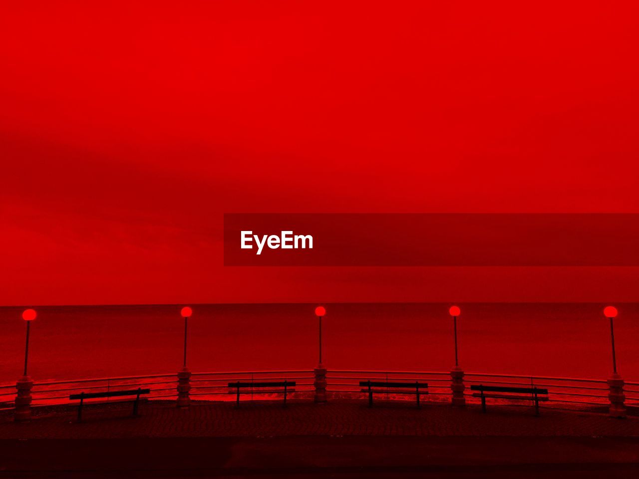 By the sea, evening light, red vision, horizon over the sea and street lamps 