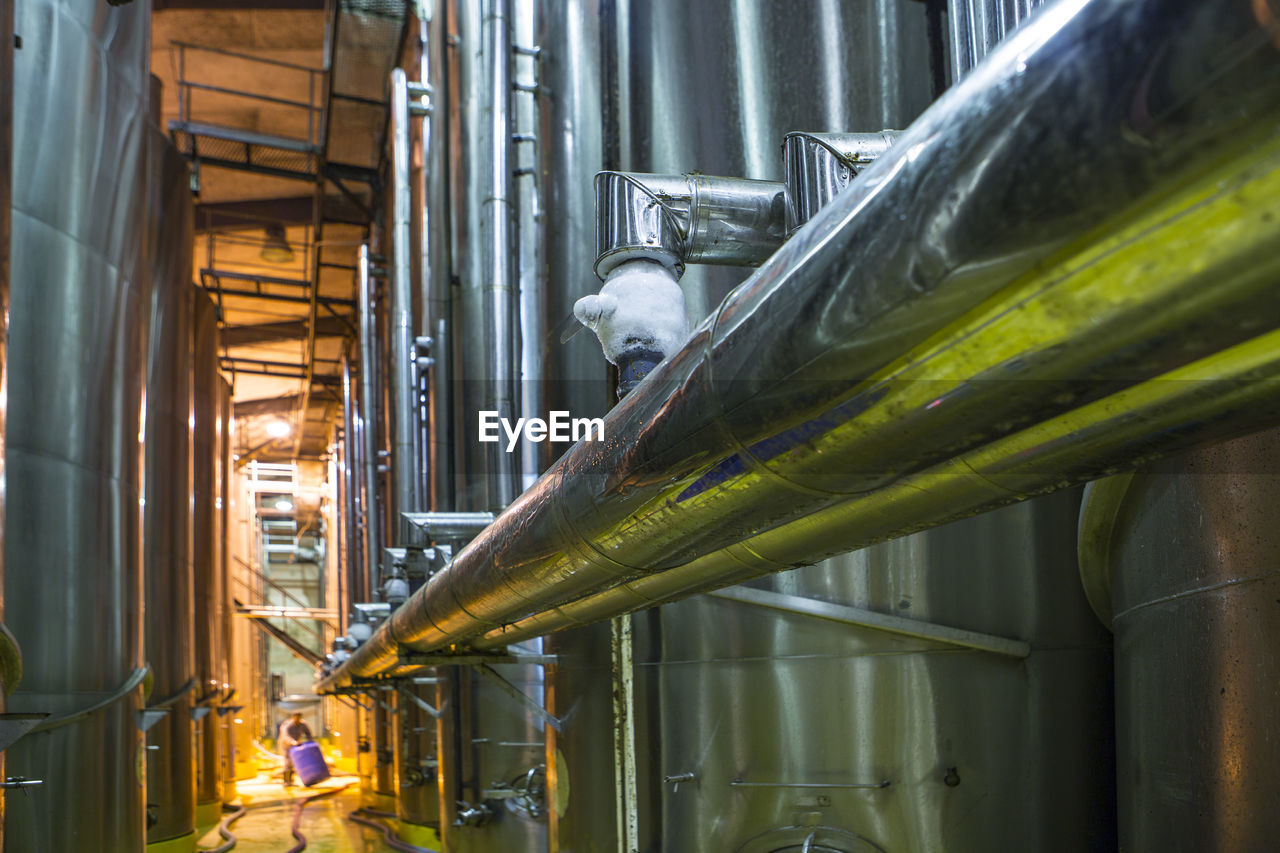 Worker controlling stainless steel tanks for food industry