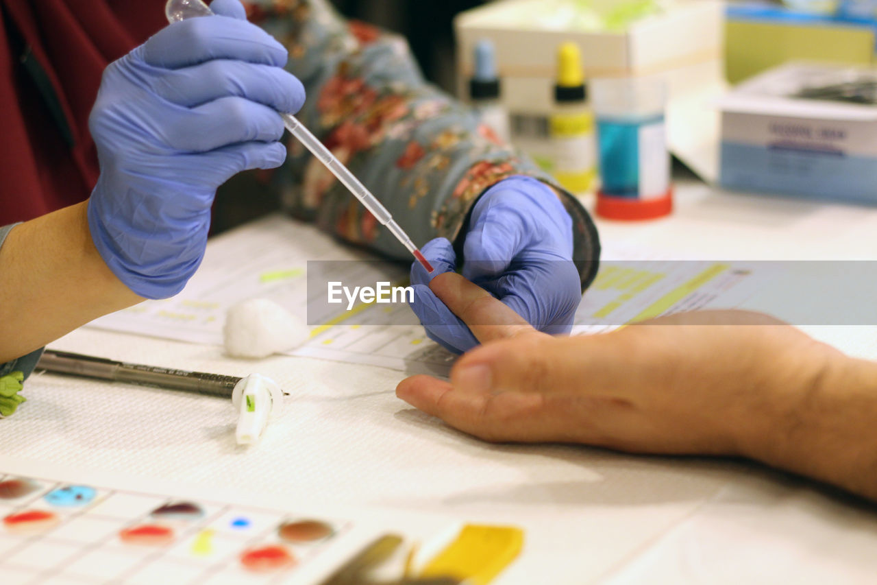 Cropped hands of doctor removing blood sample from patient finger