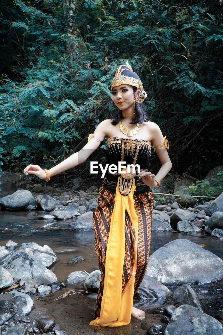 PORTRAIT OF BEAUTIFUL WOMAN STANDING ON ROCK