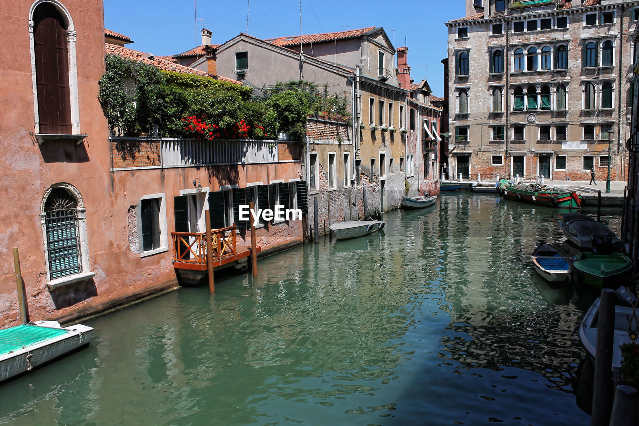 BOATS MOORED IN CANAL AMIDST CITY